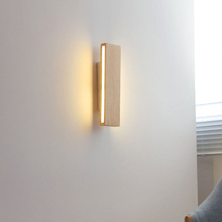 Eingeschaltete senkrechte Holzleuchte mit leuchtendem Seitenstreifen an einer weißen Wand neben einem Fenster und einem Stuhl. 15