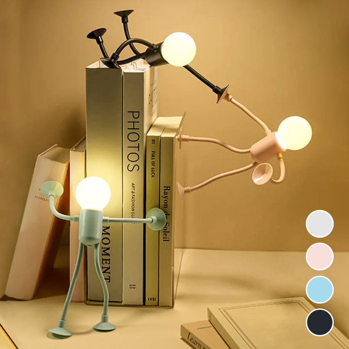 Drei leuchtende Figurenlampen in Schwarz, Rosa und Mintgrün stützen sich an einem Bücherstapel ab; rechts vier Farbpunkte zur Auswahl. 5