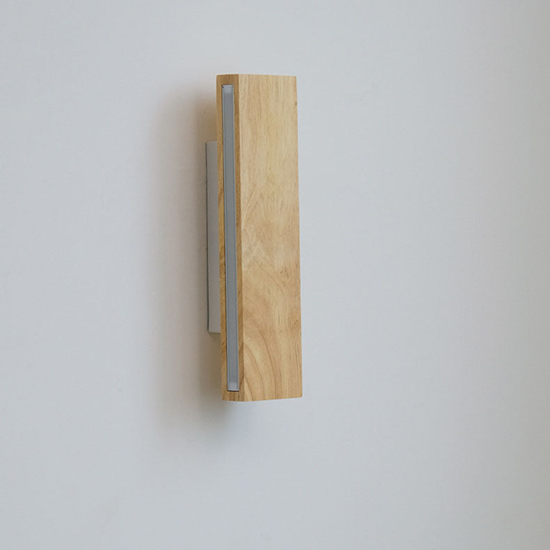 Ausgeschaltete senkrechte Holzleuchte von der Seite, mit mattem Diffusorstreifen und sichtbarer Wandhalterung an grauer Wand. 11
