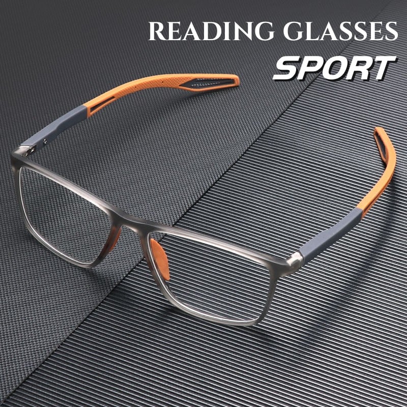 Sportliche Lesebrille mit transparent grauem Rahmen und orangefarbenen Bügelenden, schräg auf einer dunklen, gerillten Oberfläche liegend. 1