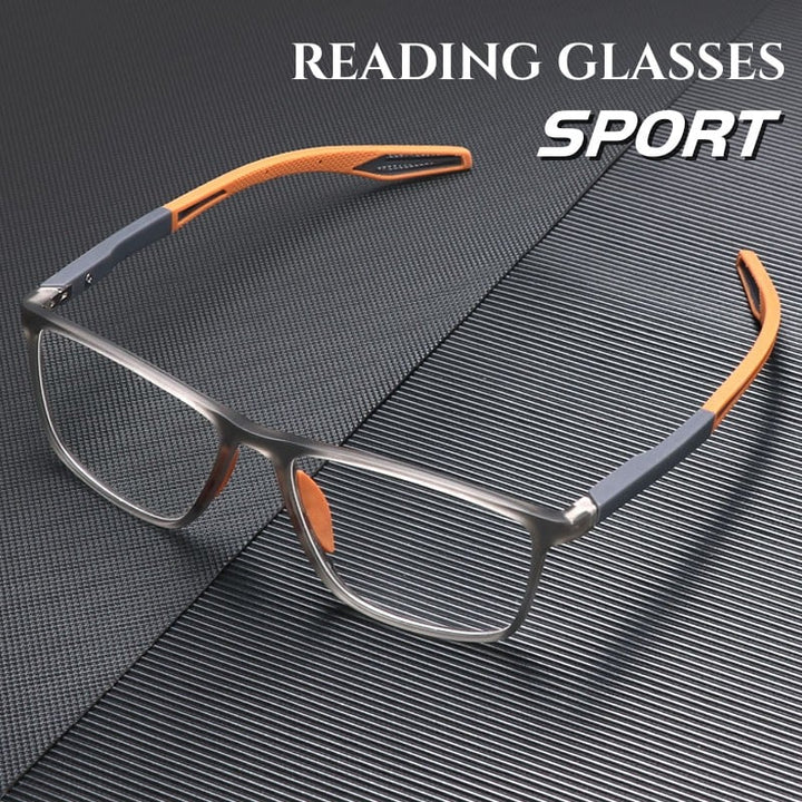 Sportliche Lesebrille mit transparent grauem Rahmen und orangefarbenen Bügelenden, schräg auf einer dunklen, gerillten Oberfläche liegend. 1
