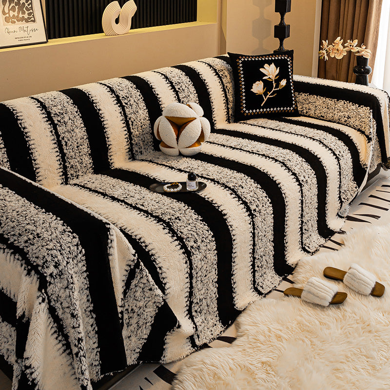 Sofa mit breit gestreiftem Bezug in Schwarz und Creme, dazu Kissen mit Blütenmotiv und flauschiger Teppich 9