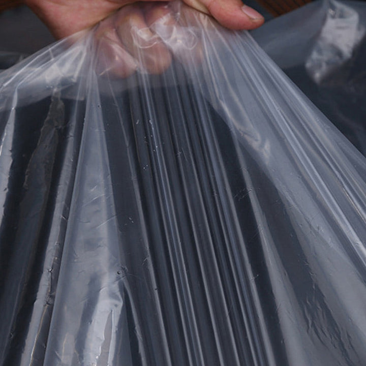 Hand hält die transparente Folie hoch, sodass die glatte, durchsichtige Oberfläche in Falten herabhängt. 6