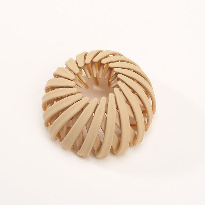 Einzelne matte Klammer in Sandbeige mit spiralförmigen Streben, freigestellt auf hellem Hintergrund. 16