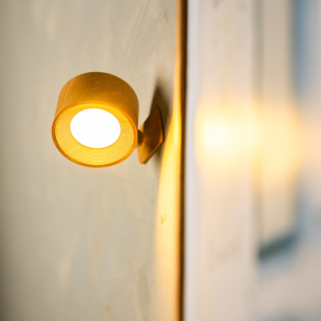 Nahaufnahme einer leuchtenden Wandlampe in Holzoptik mit fein gerilltem Innenring und heller Leuchtfläche. 15