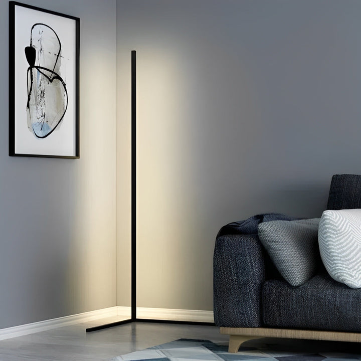 Schwarze Eckstehlampe mit sanftem Licht in einer grauen Zimmerecke neben einem dunklen Sofa und einem Gemälde 5