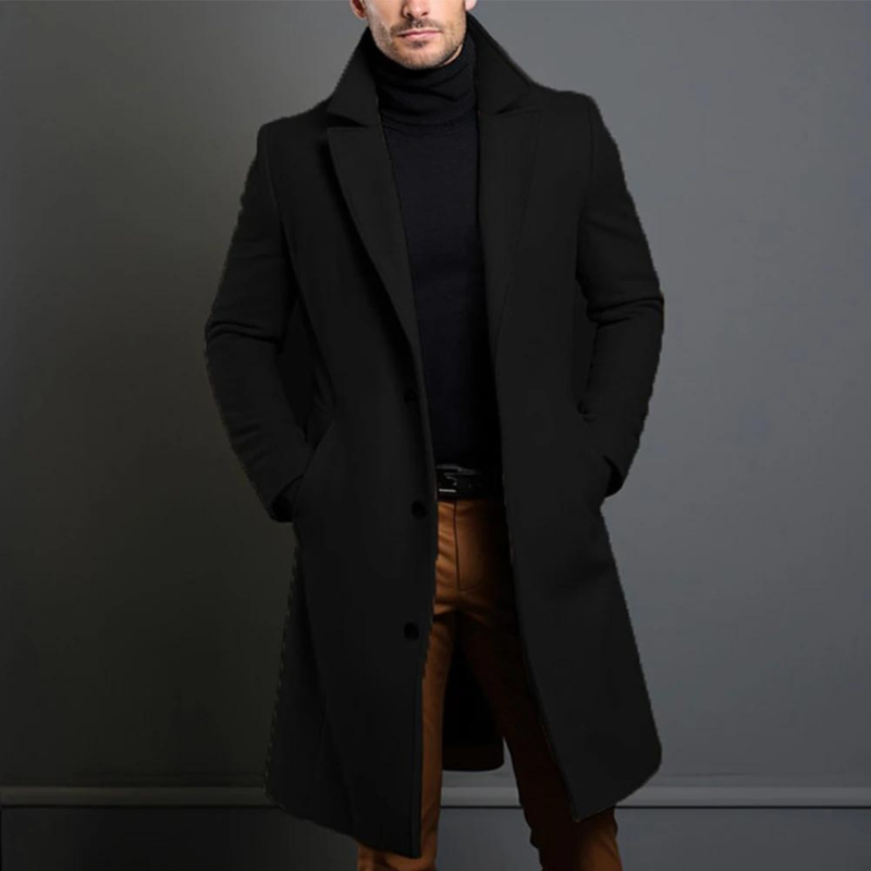 Schwarzer langer Mantel mit Reverskragen und Knopfleiste, getragen mit schwarzem Rollkragenpullover und braunen Hosen, Hände in den Taschen. 1