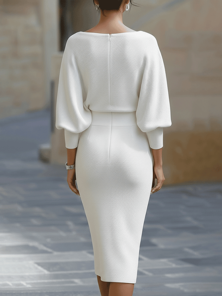 Rückansicht: Model in weißem Strickkleid mit Reißverschluss im Rücken, weiten Ballonärmeln mit Bündchen, breitem Taillenbund und schmalem Rock. 7