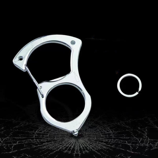 Silberner Karabiner ganz aus Edelstahl ohne Griffteil, daneben ein Schlüsselring, vor dunklem Hintergrund mit Glasrissmuster. 4