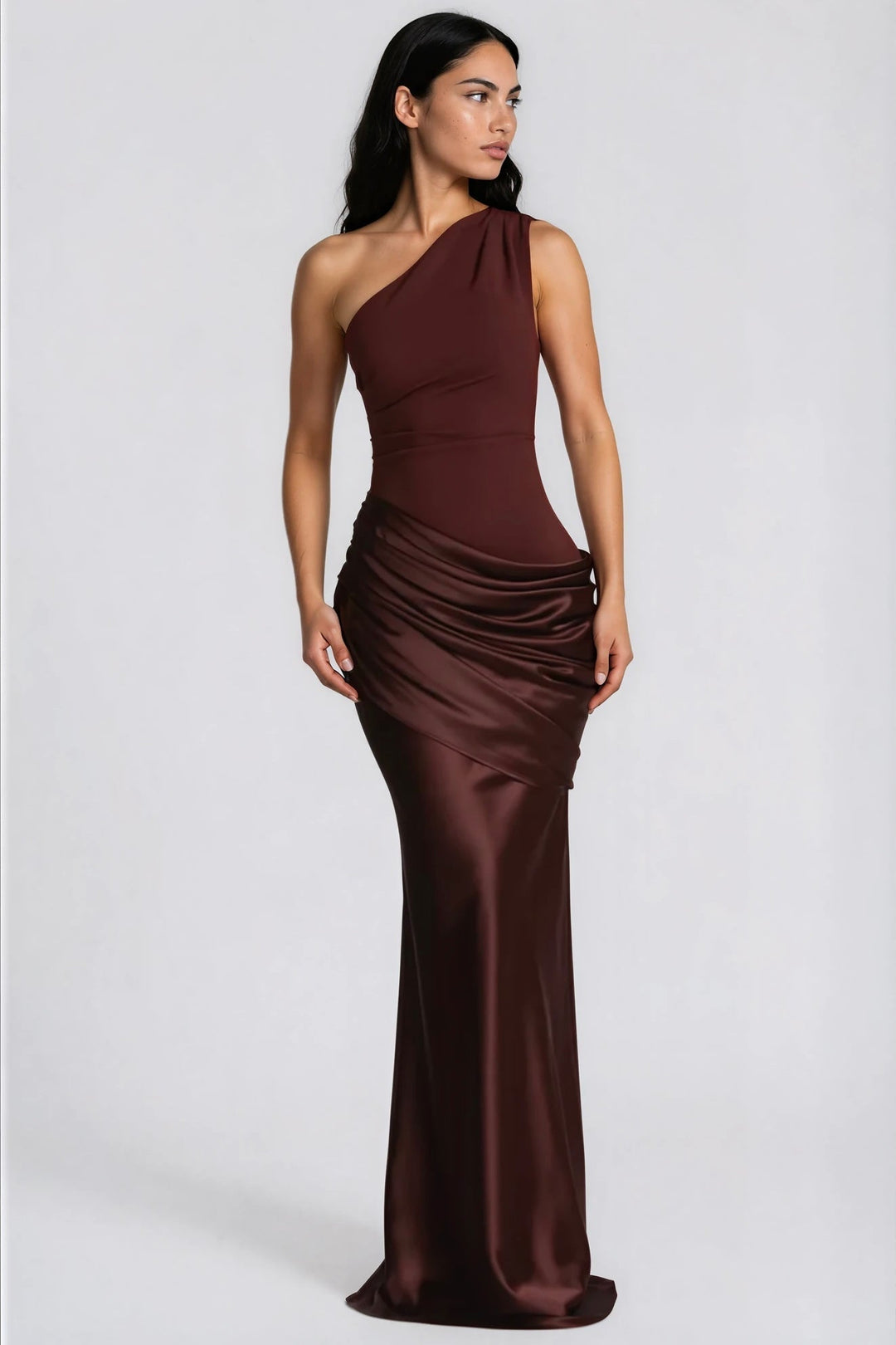 Frau im dunkelbraunen Satin-Maxikleid mit einer Schulter, Blick zur Seite, gerafftes Hüftdrapé und schmal fallender Rock. 6