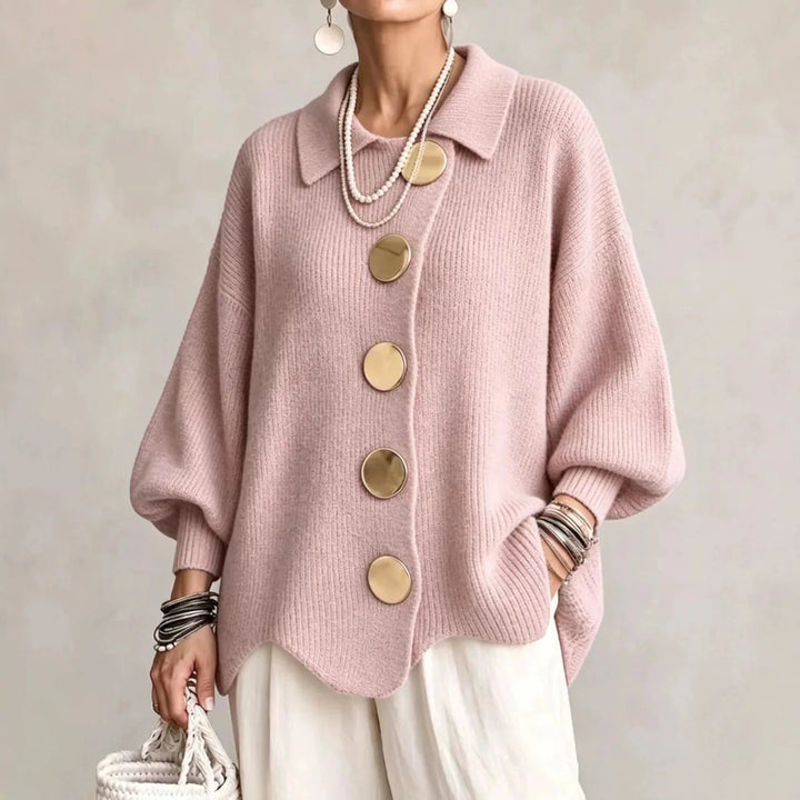 Strickjacke in zartem Rosa mit goldfarbenen Knöpfen, getragen zu weißer Hose, Perlenketten und Korbtasche. 6