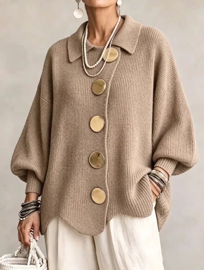 Strickjacke in Camel-Beige mit großen goldfarbenen Knöpfen, getragen zu heller Hose mit Perlenketten, leicht seitlich fotografiert. 7