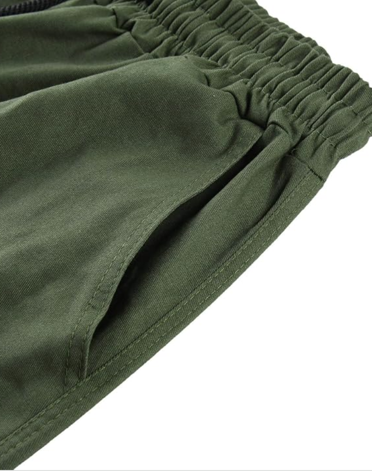 Nahaufnahme des olivgrünen Gummibunds mit schräg eingearbeiteter Eingrifftasche und Steppnähten am Hosenstoff. 13