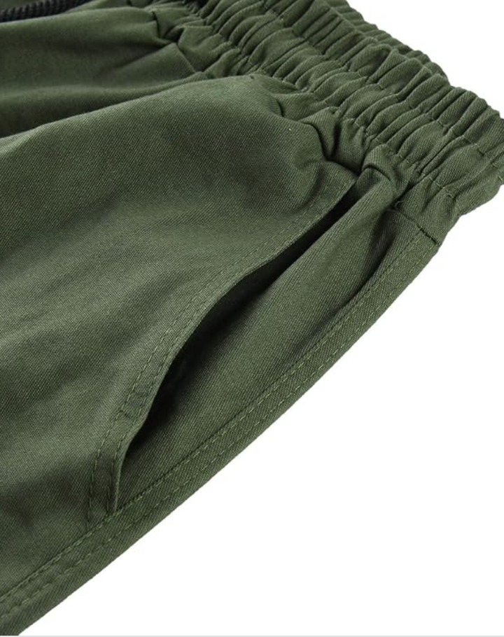 Nahaufnahme des olivgrünen Gummibunds mit schräg eingearbeiteter Eingrifftasche und Steppnähten am Hosenstoff. 13