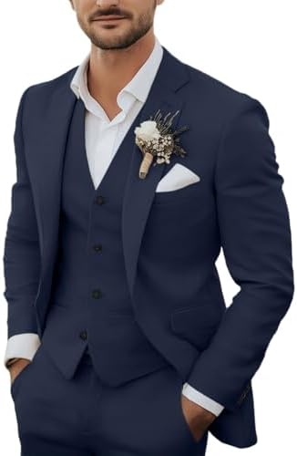 Model trägt den dreiteiligen Anzug in Marineblau mit Weste, weißem Hemd, Einstecktuch und Blumenanstecker am Revers, Hände in den Taschen. 1