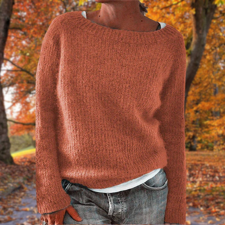 Rostroter Strickpullover mit lockerem Schnitt, getragen über weißem Shirt und grauer Jeans in einer Herbstlandschaft. 6