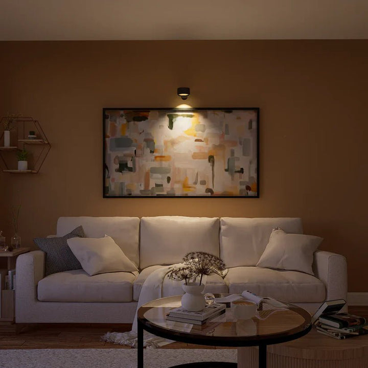 Schwarze Wandlampe über einem großen abstrakten Gemälde leuchtet das Bild über einem hellen Sofa im Wohnzimmer an. 8