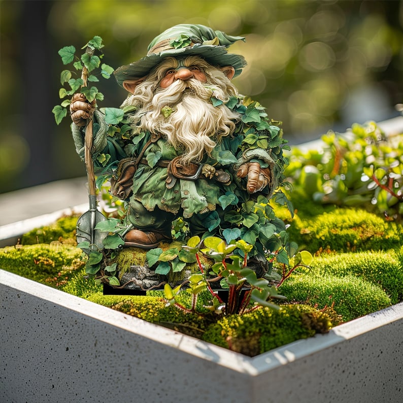 Gartenzwerg mit Bart und Spaten in einem Betonkasten mit Moos und kleinen Pflanzen im Sonnenlicht. 15
