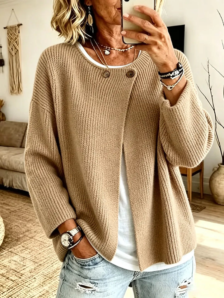 Frau macht ein Spiegelselfie in der beigen Strickjacke mit überlappender Front, weißem Shirt und Jeans 1