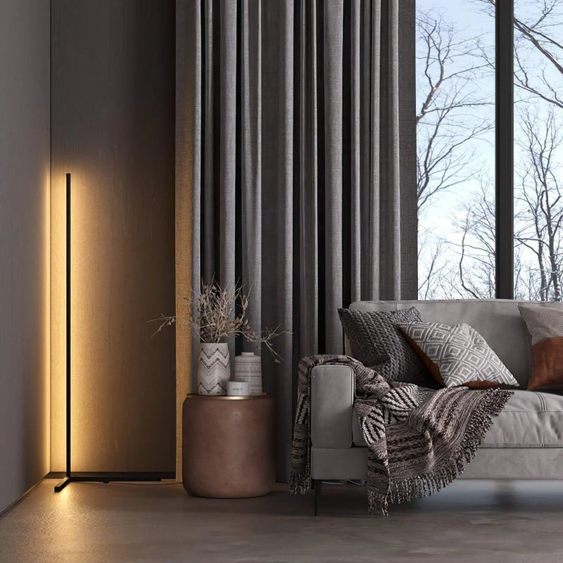 Dünne schwarze Stehlampe mit warmem Licht in einem Wohnzimmer neben grauem Vorhang, Beistelltisch und Sofa 3