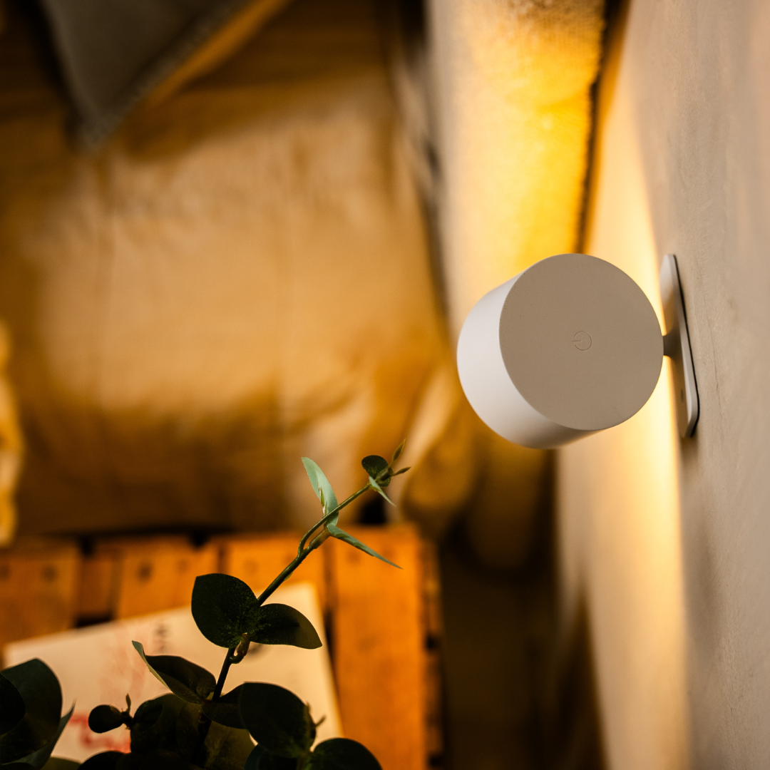 Rückseite der weißen Wandlampe von der Seite, mit kleiner Touch-Taste auf dem runden Deckel und Wandhalterung. 13