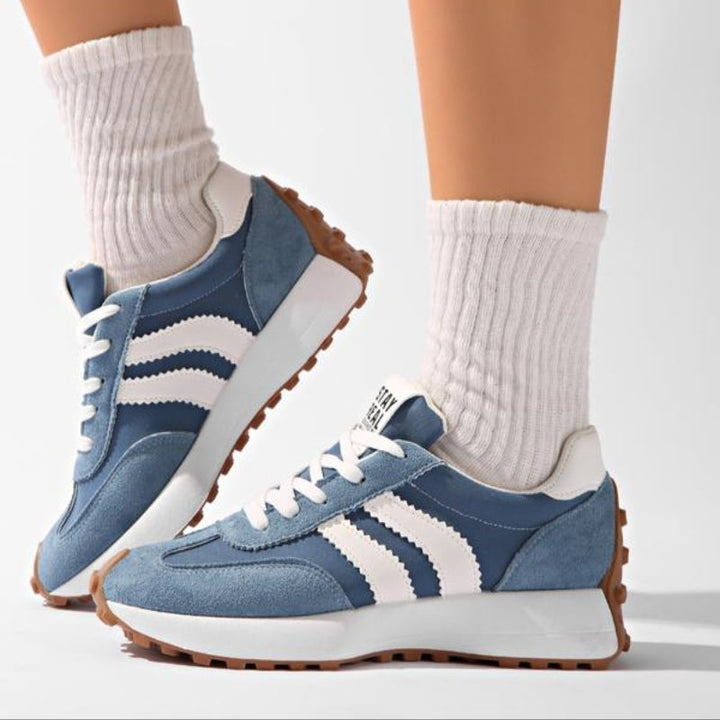 Blaue Sneaker mit weißen Streifen, getragen mit weißen Rippensocken, Seitenansicht in Schrittpose 8