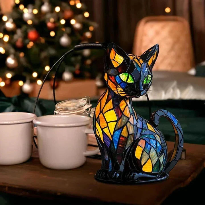 Katzenlampe auf einem Holztisch neben weißen Bechern, im Hintergrund ein geschmückter Weihnachtsbaum mit Lichterkette 3
