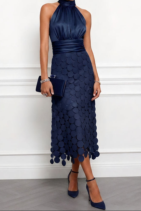 Das Kleid in dunklem Marineblau, Satinoberteil mit gerafftem Bund und Scheibenapplikationen am Rock, dazu dunkle Clutch und Pumps. 4