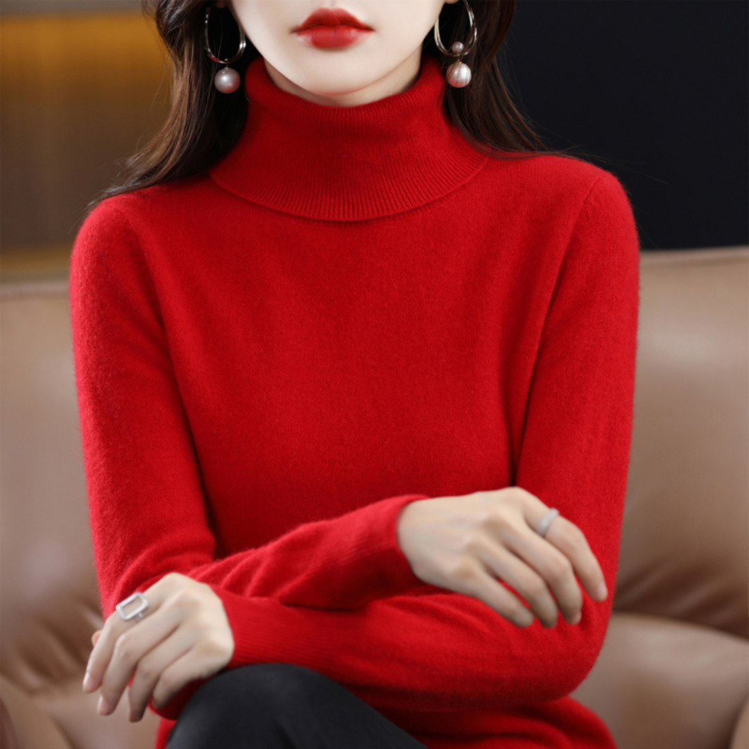 Roter Rollkragenpullover am sitzenden Model, die Arme locker übereinandergelegt, kombiniert mit schwarzer Hose. 9