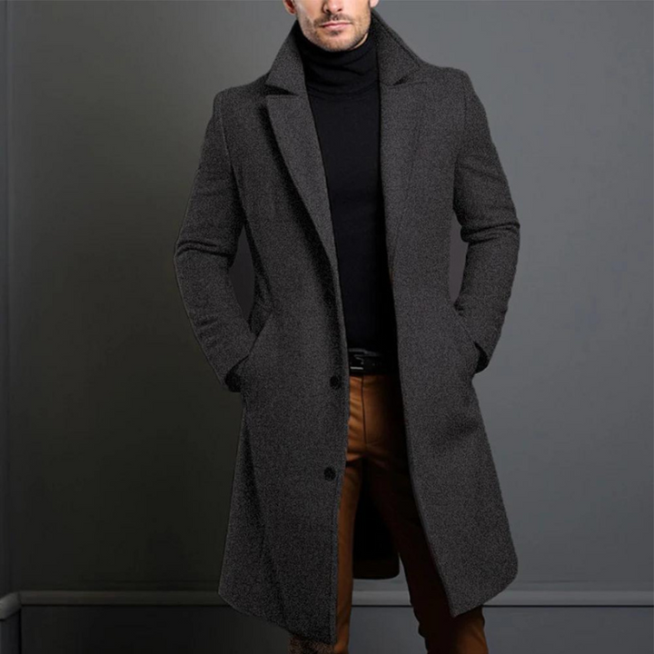 Dunkelgrauer, leicht melierter langer Mantel mit Reverskragen, getragen über schwarzem Rollkragenpullover und brauner Hose. 3