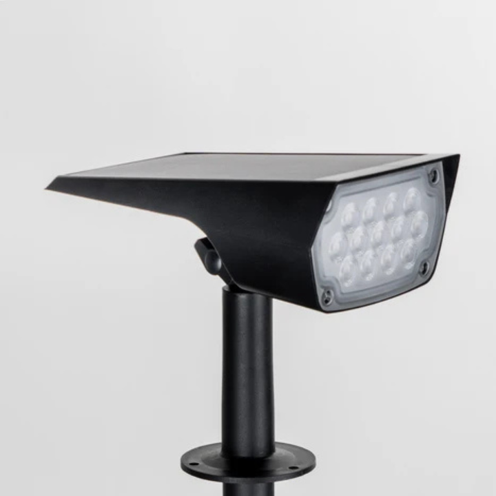 Nahaufnahme des schwarzen Strahlerkopfs mit Solarpanel oben und mehreren LEDs hinter der Frontscheibe, auf dem Erdspieß vor hellem Hintergrund. 4