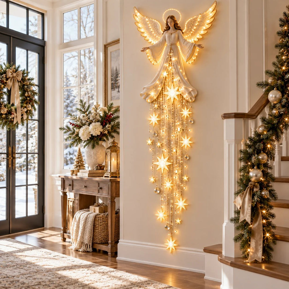 Beleuchteter Engel mit herabfallenden Sternen an der Wand eines hellen Eingangsbereichs, neben Konsolentisch, Weihnachtskranz und Treppengirlande. 2
