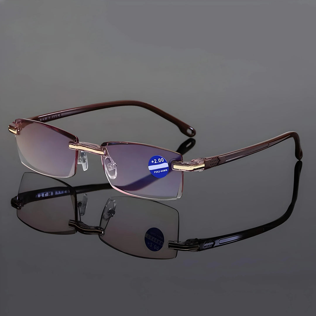 Lesebrille mit braunen Bügeln und goldfarbenen Beschlägen auf spiegelnder grauer Fläche, die Farbvariante Braun im Vergleich zu Schwarz. 7