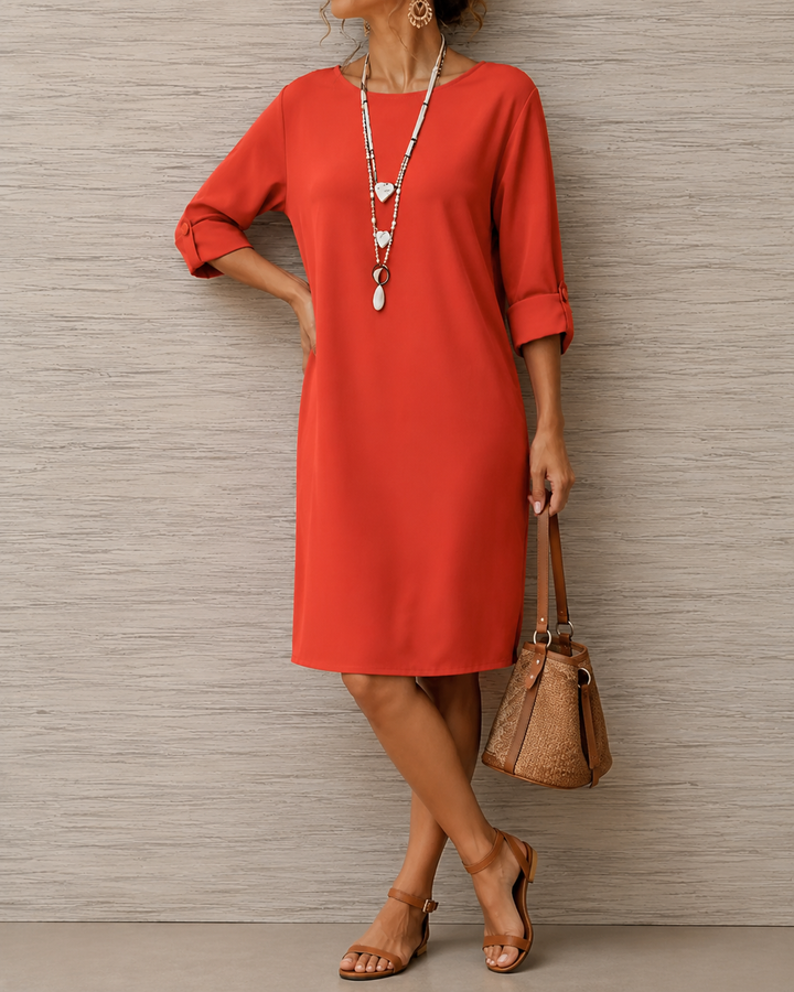 Rotes Kleid mit Knopfdetail an den umgeschlagenen Ärmeln, Hand in die Hüfte gestützt, dazu Beuteltasche 4