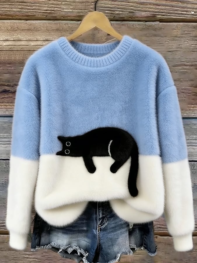 Flauschiger Pullover in Hellblau mit weißem Unterteil und aufgenähter schwarzer Katze, an Holzbügel vor Holzwand 1