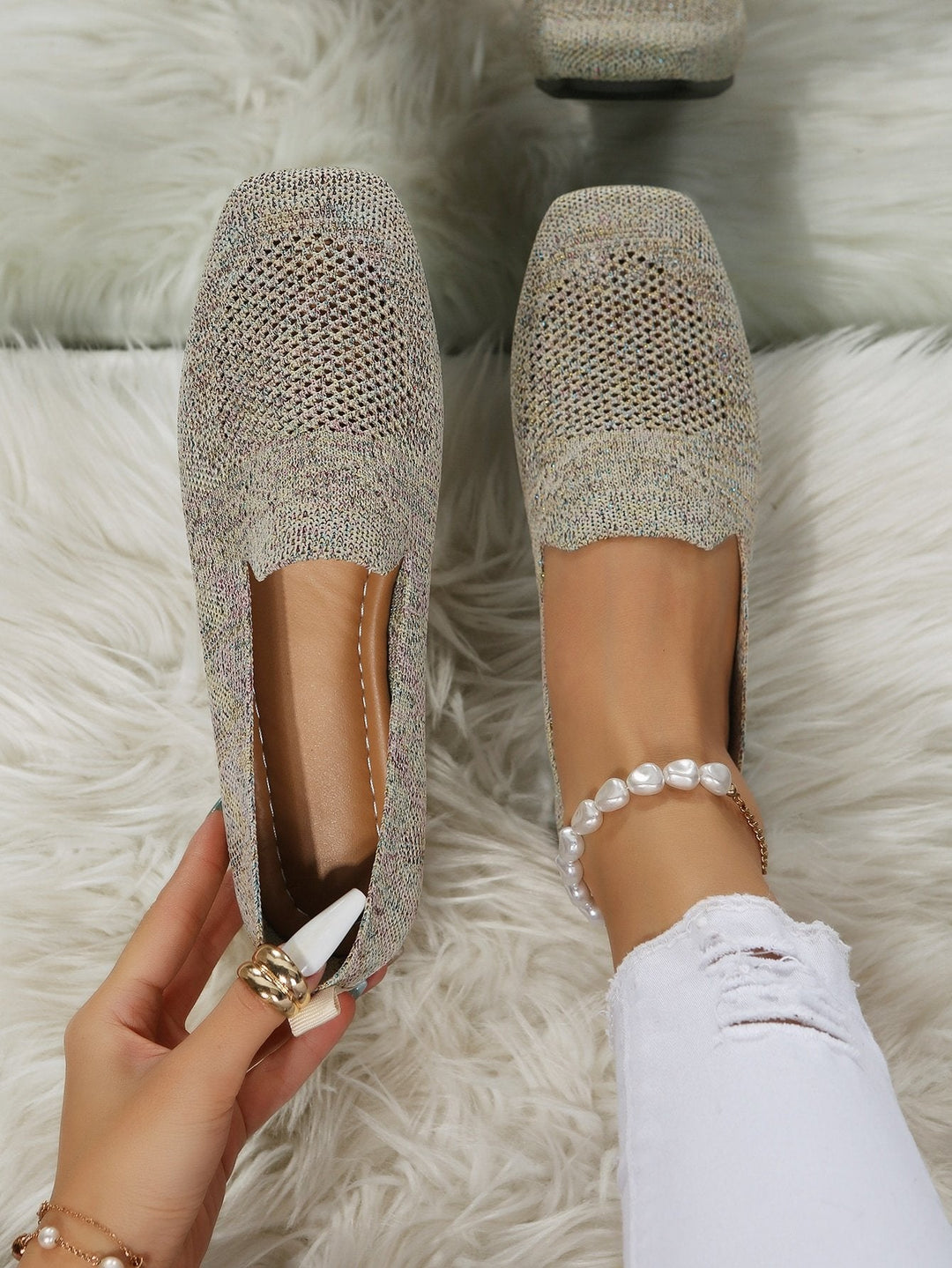 Von oben fotografiert: beige-melierte Slip-On-Schuhe mit eckiger Spitze und luftigem Netzeinsatz, ein Schuh am Fuß, einer in der Hand auf weißem Plüsch. 21