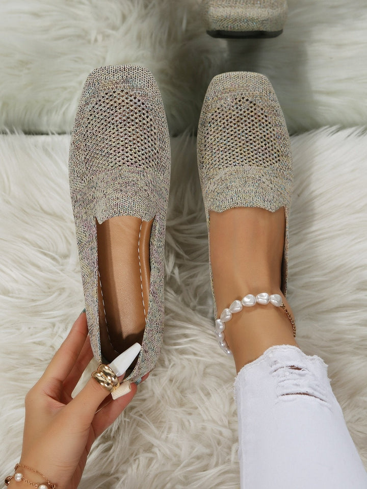 Von oben fotografiert: beige-melierte Slip-On-Schuhe mit eckiger Spitze und luftigem Netzeinsatz, ein Schuh am Fuß, einer in der Hand auf weißem Plüsch. 21