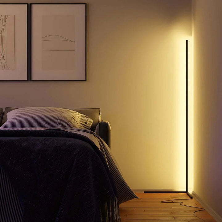 Warm leuchtende Stehlampe in der Zimmerecke neben einem Bett, darüber zwei gerahmte Bilder an der Wand 4