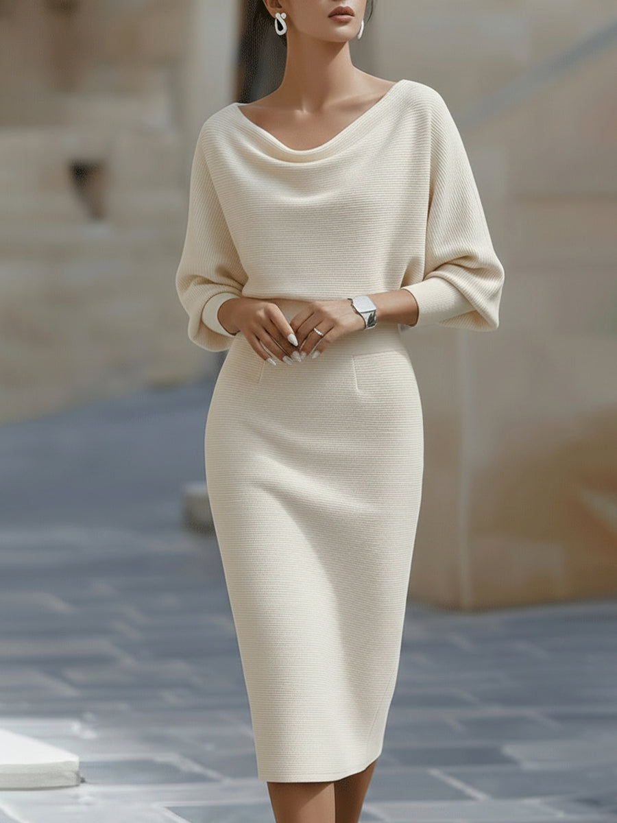 Frontansicht: Model in cremefarbenem Strickkleid mit weichem Wasserfallausschnitt, Fledermausärmeln und schmal geschnittenem Rock bis zur Wade. 3
