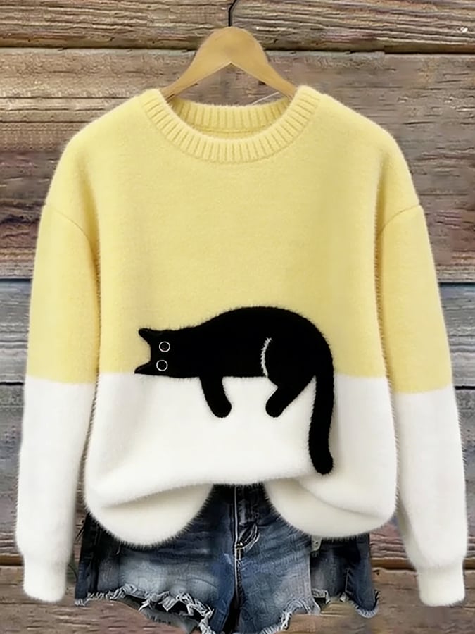 Flauschiger Pullover in Hellgelb mit weißem Unterteil und aufgenähter schwarzer Katze, an Holzbügel vor Holzwand 7