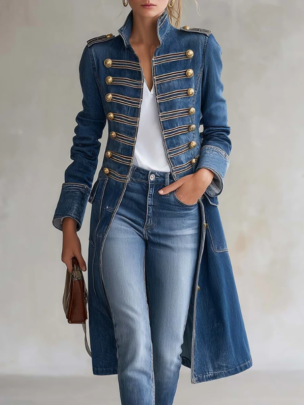Frontansicht des blauen Jeansmantels mit goldenen Knöpfen und Zierlitzen, getragen mit heller Jeans, weißem Shirt und brauner Handtasche. 1