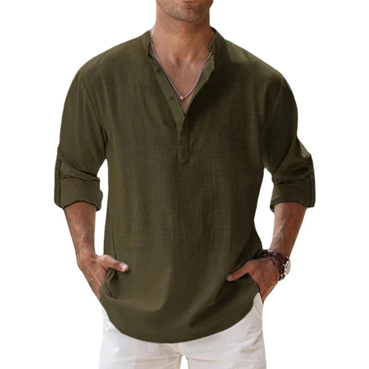 Mann trägt das lockere Henley-Shirt in Olivgrün mit Knopfleiste und aufgerollten Ärmeln, dazu weiße Hose. 8