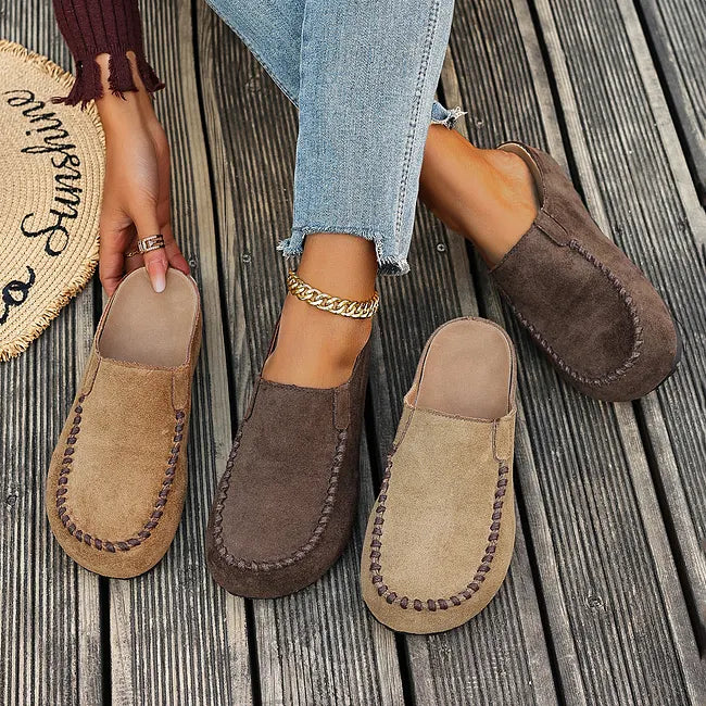 Slipper in Beige und Dunkelbraun nebeneinander auf Holzdielen, teils getragen, teils mit sichtbarem hellem Fußbett. 7