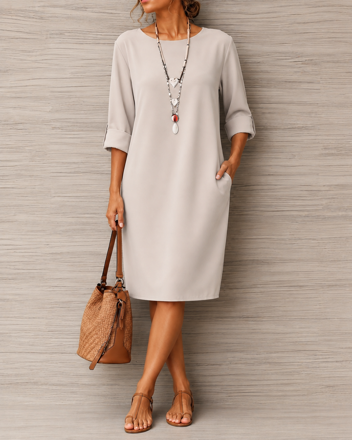 Hellgraues Kleid mit hochgeschlagenen Ärmeln, Hand in der Tasche, dazu Korbtasche und Zehentrenner-Sandalen 8