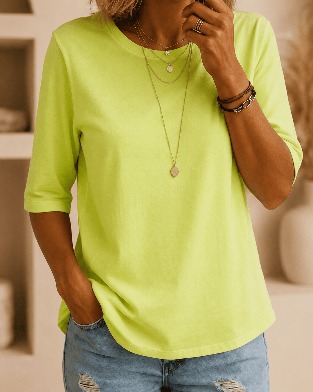 Frau trägt das neongrüne Shirt mit halben Ärmeln zu Jeans, dazu mehrere zarte Halsketten und Armbänder, Vorderansicht. 1