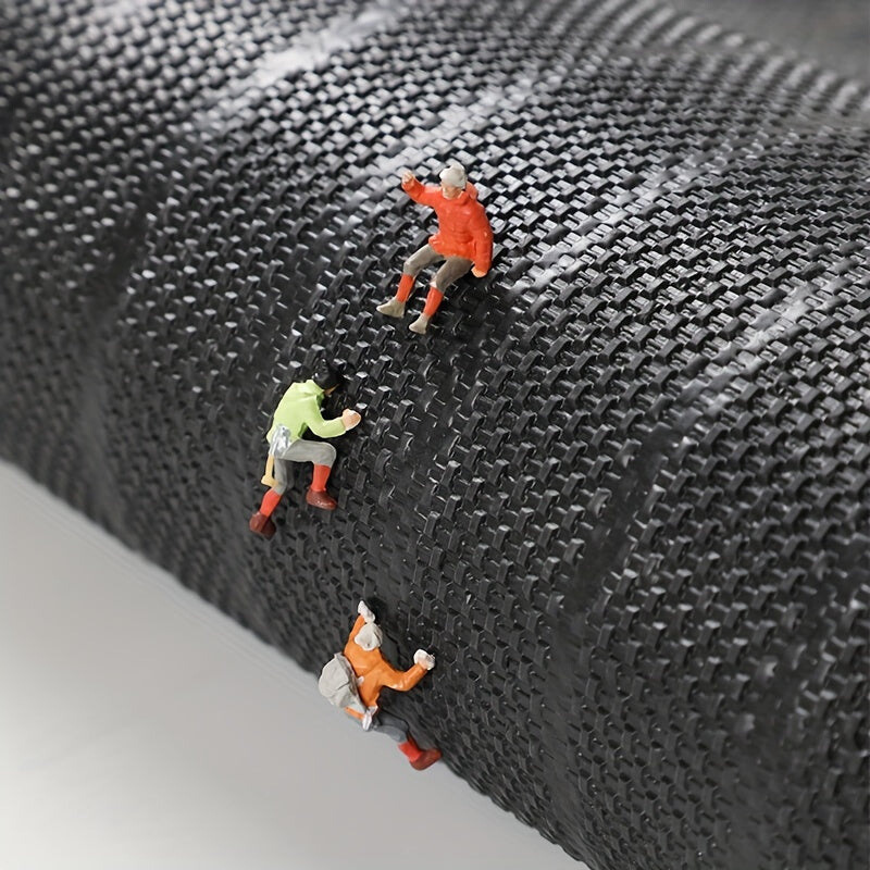 Rückseite der aufgerollten Matte mit grobem, gewebtem Muster, auf dem drei Miniatur-Kletterfiguren in bunter Kleidung emporsteigen. 7