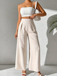 Frau in weißem Crop-Top und beigen High-Waist-Hosen, Sommermode, eleganter Look.