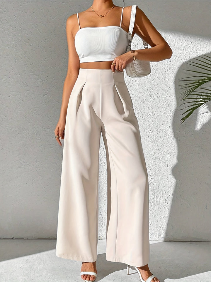 Frau in weißem Crop-Top und beigen High-Waist-Hosen, Sommermode, eleganter Look.