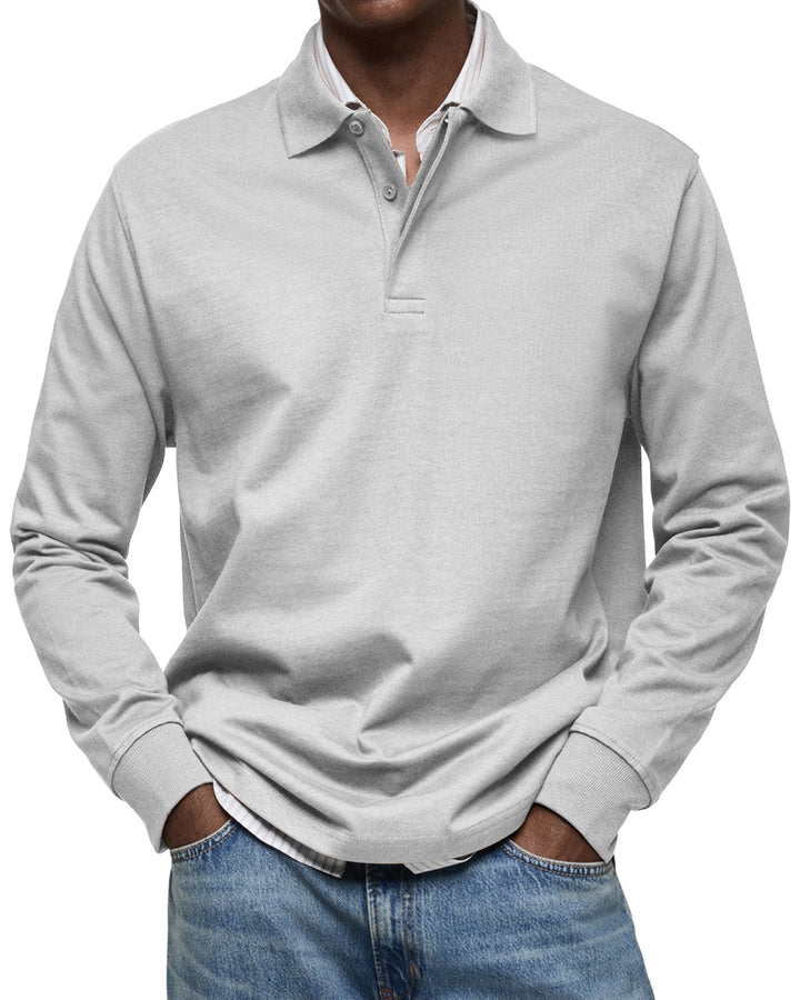 Langarm-Poloshirt in Hellgrau, Frontansicht am Model, Hände in den Jeanstaschen, Hemdkragen und Saum des Hemds sichtbar. 5