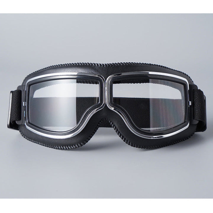 Frontansicht der Brille mit schwarzer Lederpolsterung, Chromrahmen und klaren Gläsern, das elastische Band seitlich sichtbar. 16